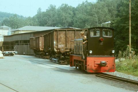 Ns 4 199 007 rangiert am 15.08.1985 in der Anschlussbahn der Papierfabrik Wilischthal mit zwei auf Rollfahrzeugen aufgebockten Es-Wagen.