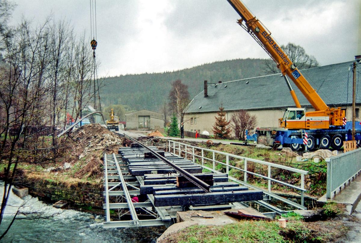 Mit dem Kran werden auch gleich die Schienen auf den eingebauten Brückenüberbau gehoben.