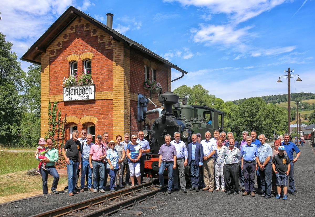 Gruppenfoto mit Jubilar (im Hintergrund) und Teilnehmern der Feier und Sonderfahrt am Wasserhaus in Steinbach.