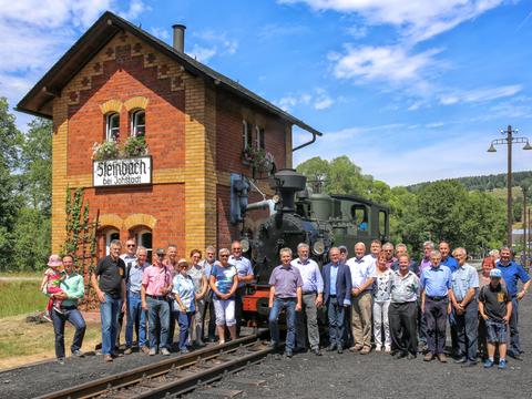 Gruppenfoto mit Jubilar (im Hintergrund) und Teilnehmern der Feier und Sonderfahrt am Wasserhaus in Steinbach.