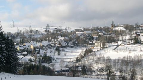Blick auf die schneebedeckte Kulisse der Bergstadt Jöhstadt mit Lokschuppen im unteren Bilddrittel und St. Salvator-Kirche in der Bildmitte