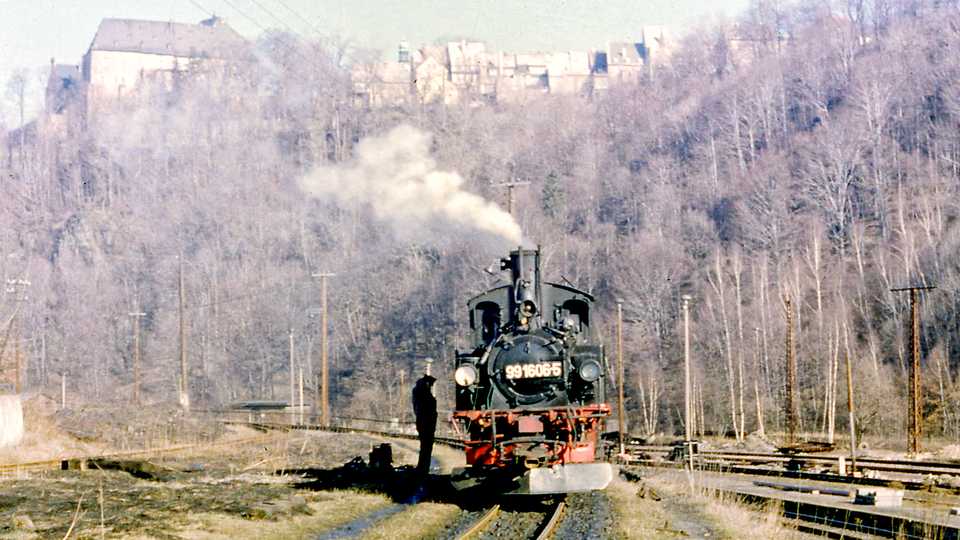 Vor der Kulisse des Wolkensteiner Schlosses steht 99 1606-5 am 10. März 1986 im Güterteil des Bahnhofs Wolkenstein.
