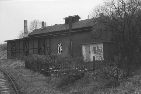 Lokschuppen mit eingeschlagenen Fenstern und ein verwilderter Eisenbahnergarten mit Laube neben dem noch liegenden Einfahrtgleis in den Bahnhof Jöhstadt.