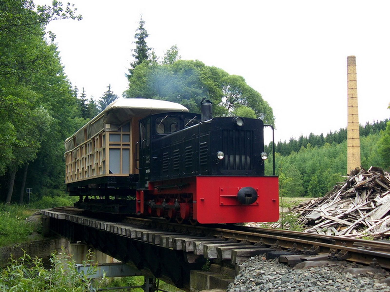 Der werkstattneue Holzwagenkasten von 970-507 auf der Brücke in Schlössel hinter Ns4 199 007-6 auf einem Rollfahrzeug.