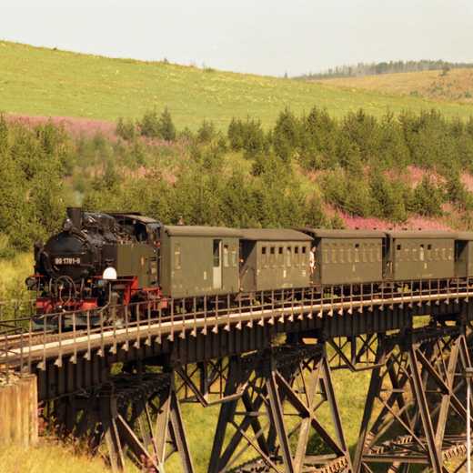 Während ihres zweiten, von 1986 bis 1991 währenden, Einsatzes zwischen Cranzahl und Oberwiesenthal kommt die Lok 99 1781-6 der Deutschen Reichsbahn dem Fotografen hier mit einem Personenzug auf dem Oberwiesenthaler Viadukt entgegen.