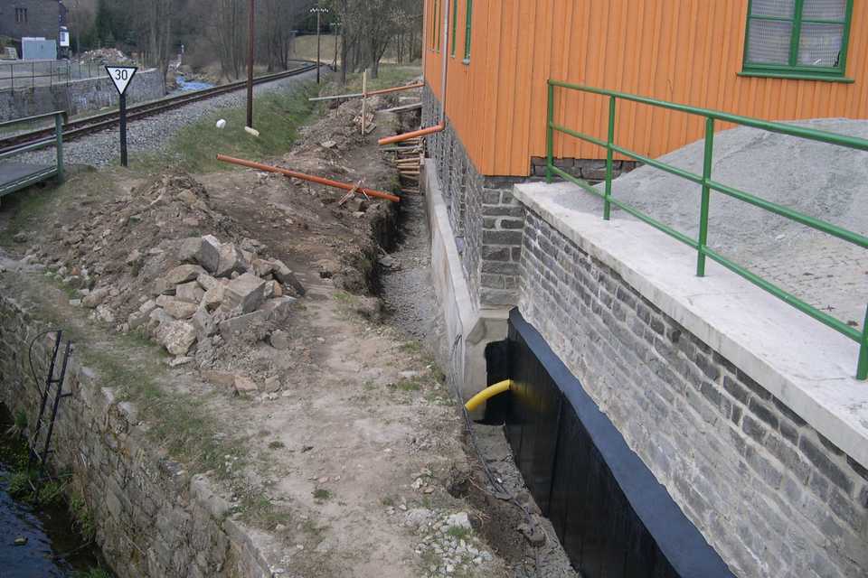 Nach der Betonierung einer Abdichtung an das Fundament der Lagerhalle wird der Beton noch mit einem Teeranstrich versehen.