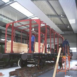 In den neu aufgebauten Stahlträgerrahmen werden die ersten Beplankungsbretter eingebaut.