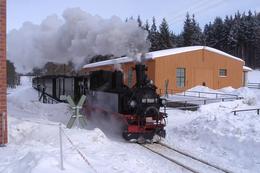 Der Sonne entgegen fährt dieser Personenzug durch hohe Schneehaufen in Richtung Jöhstadt.