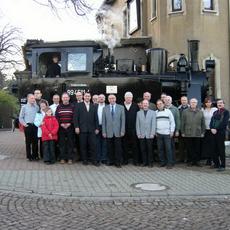 Gruppenfoto mit Gästen an der ersten Schmalspurlok in Falkenau, wenige Meter neben den Hauptbahngleisen.