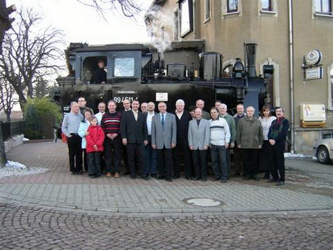 Gruppenfoto mit Gästen an der ersten Schmalspurlok in Falkenau, wenige Meter neben den Hauptbahngleisen.