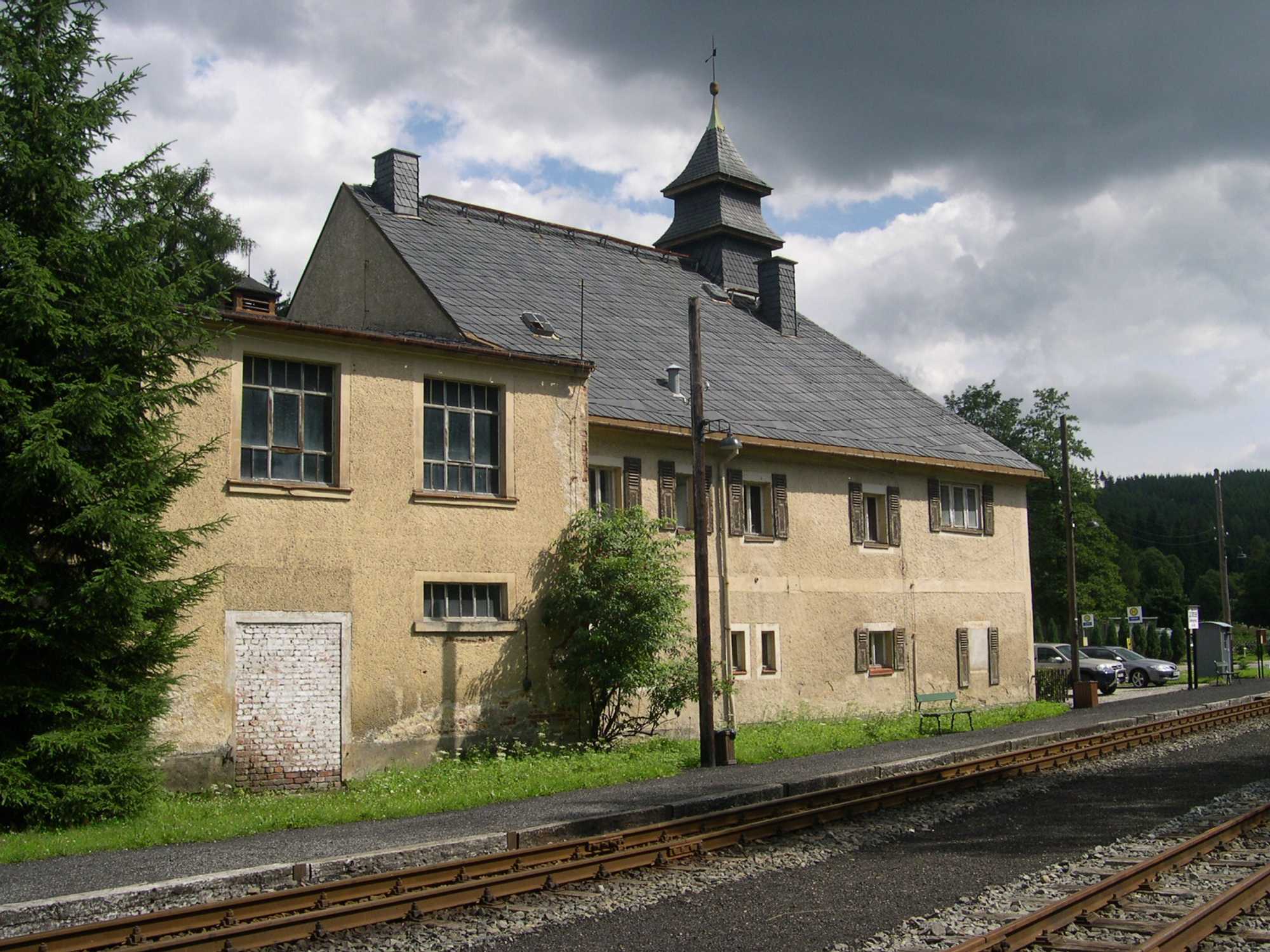 Bahnsteig in Schlössel mit ehemaligem Fabrikgebäude und Fabrikantenvilla im Hintergrund.
