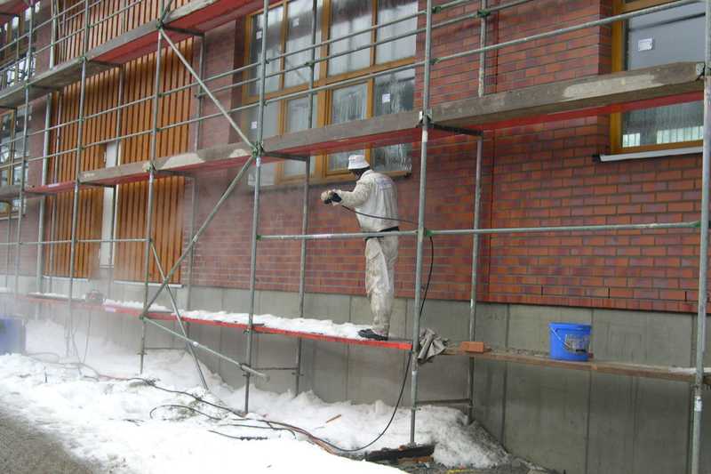 An der Hallenfassade wird das Klinkermauerwerk abgespritzt und von Mörtelresten gereinigt.