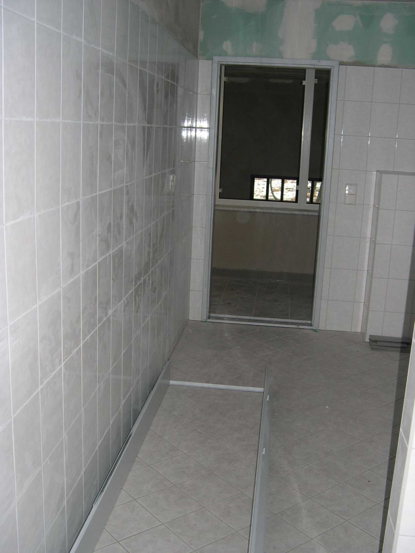 Der Sanitärraum im Obergeschoß des Mehrzweckgebäudes hat seine Türzarge erhalten, auf dem Fußboden liegt die Türzarge für die Toilette.