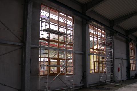 Der Einbau der Fensterscheiben erfolgt über Standgerüste im Halleninneren und über das Außengerüst.