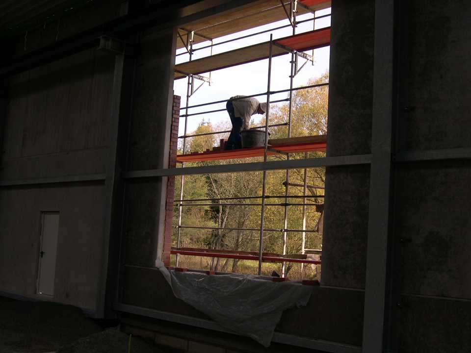 Blick durch die Fensteröffnung der Fahrzeughalle auf die Arbeiten am Klinkermauerwerk.