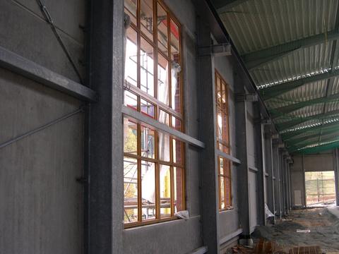 Eingesetzte Fensterrahmen in den ersten beiden Fensteröffnungen entlang der Front der Fahrzeughalle.