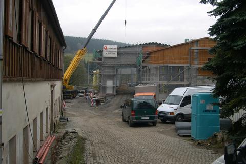 Blick von der Einfahrt an der Schlösselstraße auf die Baustelle. Im Giebelbereich sind die Kanten des Trapezbleches zu erkennen.
