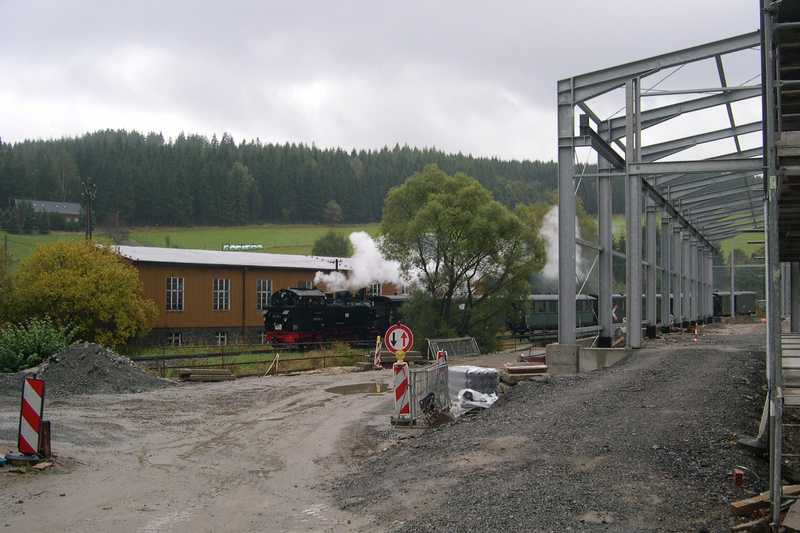 Ein Personenzug mit 99 715 passiert die Baustelle der Ausstellungs- und Fahrzeughalle.