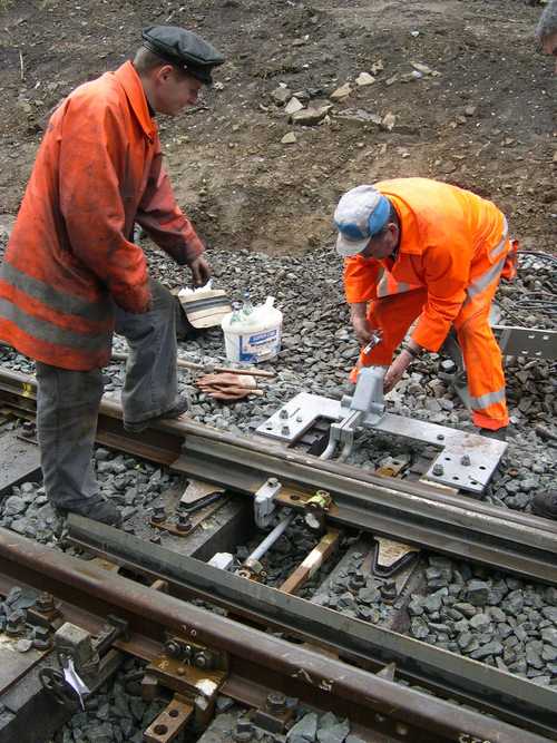 Montagearbeiten der Weichenstell- und Schließvorrichtung an der Anschlussweiche im Streckengleis.