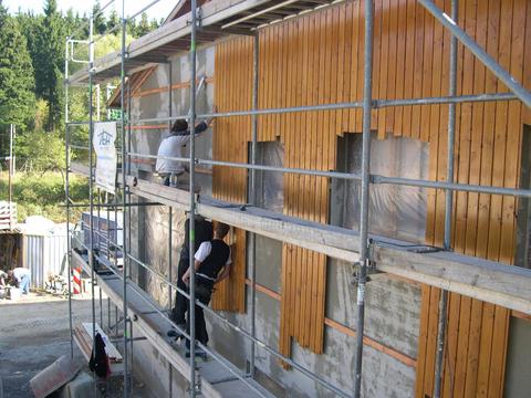 Die Holzverschalung der Giebelwand des Mehrzweckgebäudes nimmt sichtbare Fortschritte an.