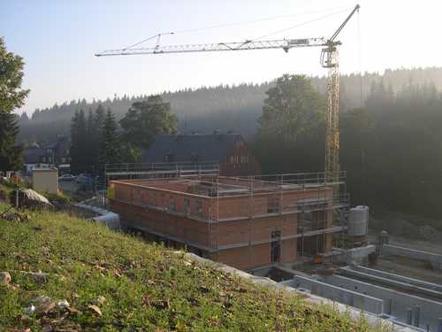 Blick auf den Rohbau des Mehrzweckgebäudes im Morgennebel, bevor die Arbeiten am Dach begonnen haben.