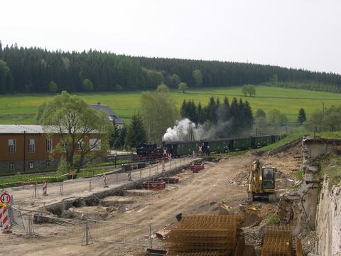 Der Personenzug der Museumsbahn passiert den Bahnübergang an der Baustelle.