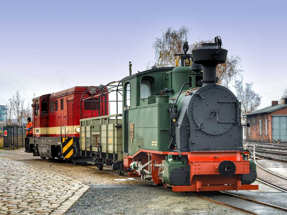 Die L45H der Sächsischen Dampfeisenbahn-Gesellschaft rangiert die I K Nr. 54 und den „Bänkelwagen“ 4333K der Preßnitztalbahn in das Gebäude des Tagungszentrums der Sächsischen Wirtschaft.