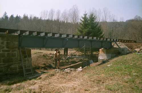 Mittels Gerüst werden die Balken über dem Mühlgraben an der Brücke befestigt.