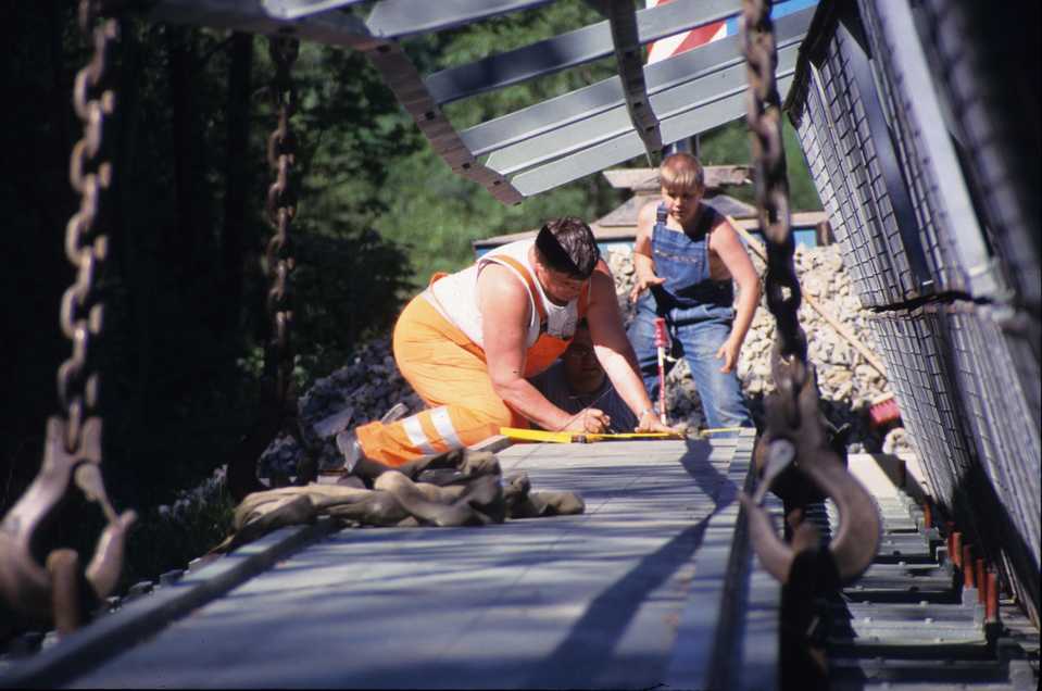 Maßkontrolle des Brückenüberbaus, während die Brücke noch an vier Haken hängt.